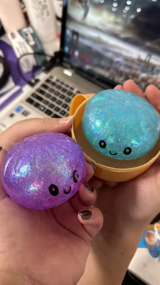 Customer holding blue and purple glitter dumpling squishies